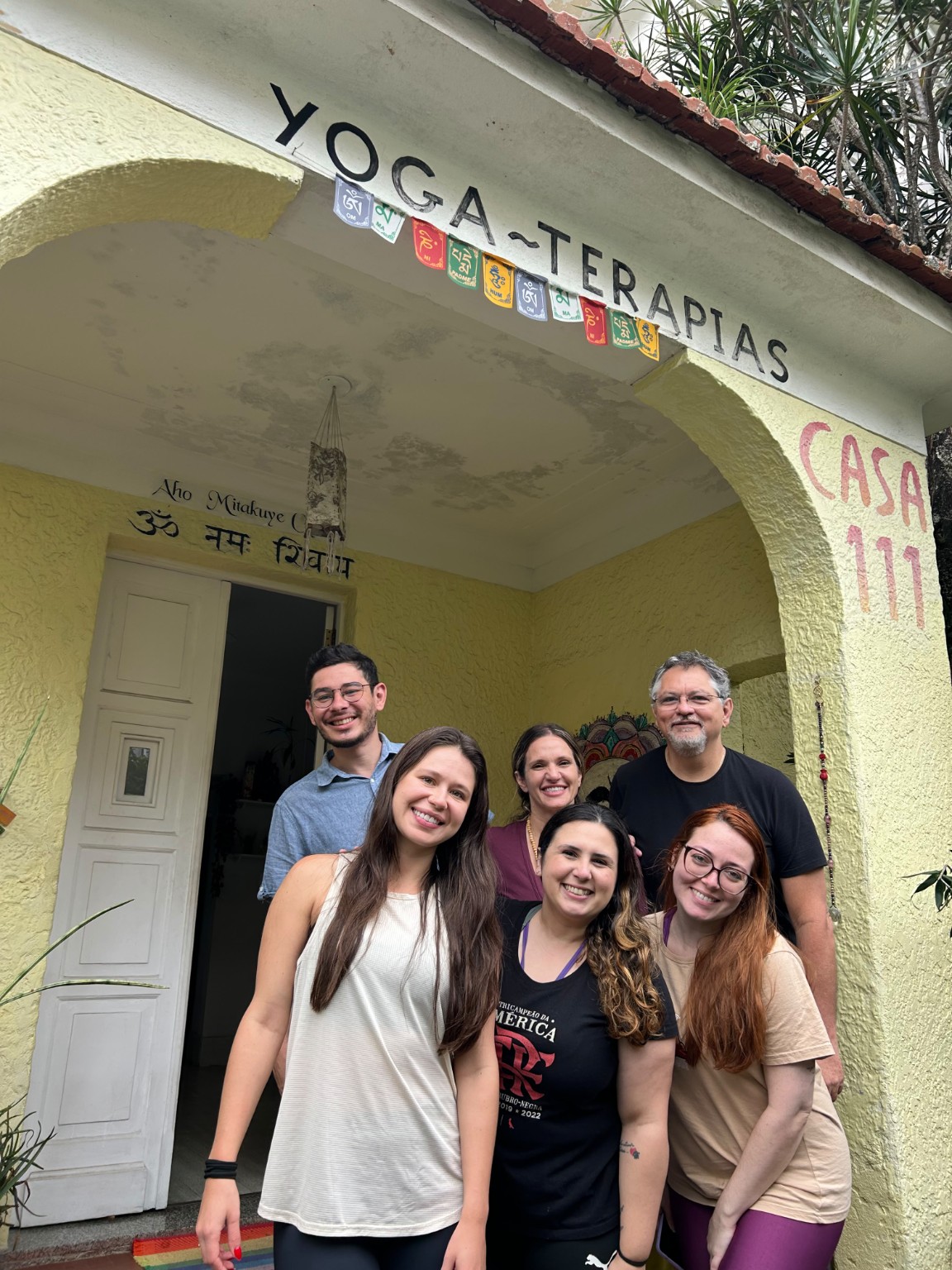 Participantes sorrindo juntos na entrada da Casa 111