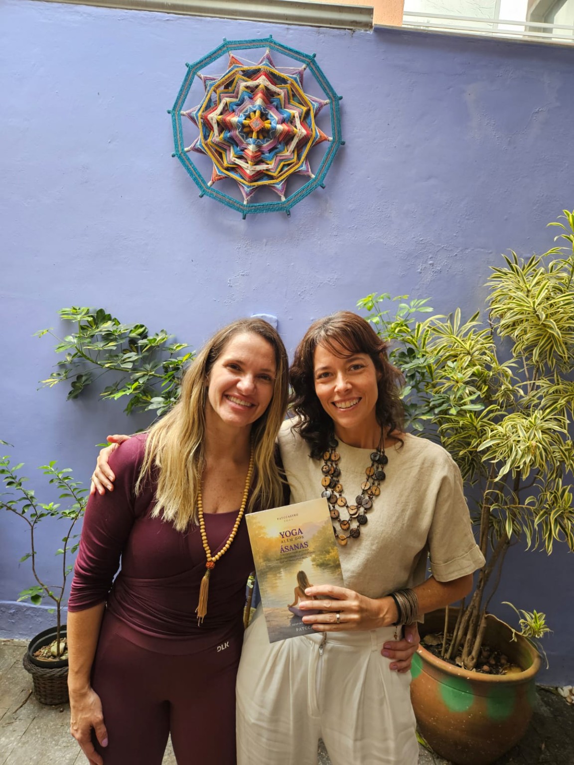 Duas participantes com um exemplar do livro no jardim da Casa 111