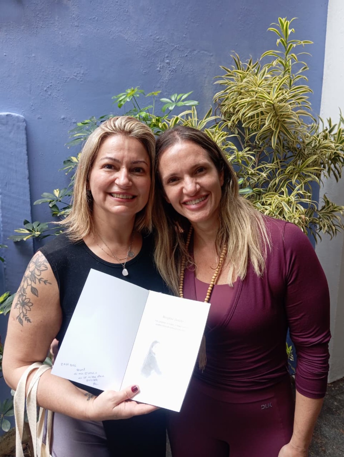 Duas participantes sorrindo com um exemplar do livro
