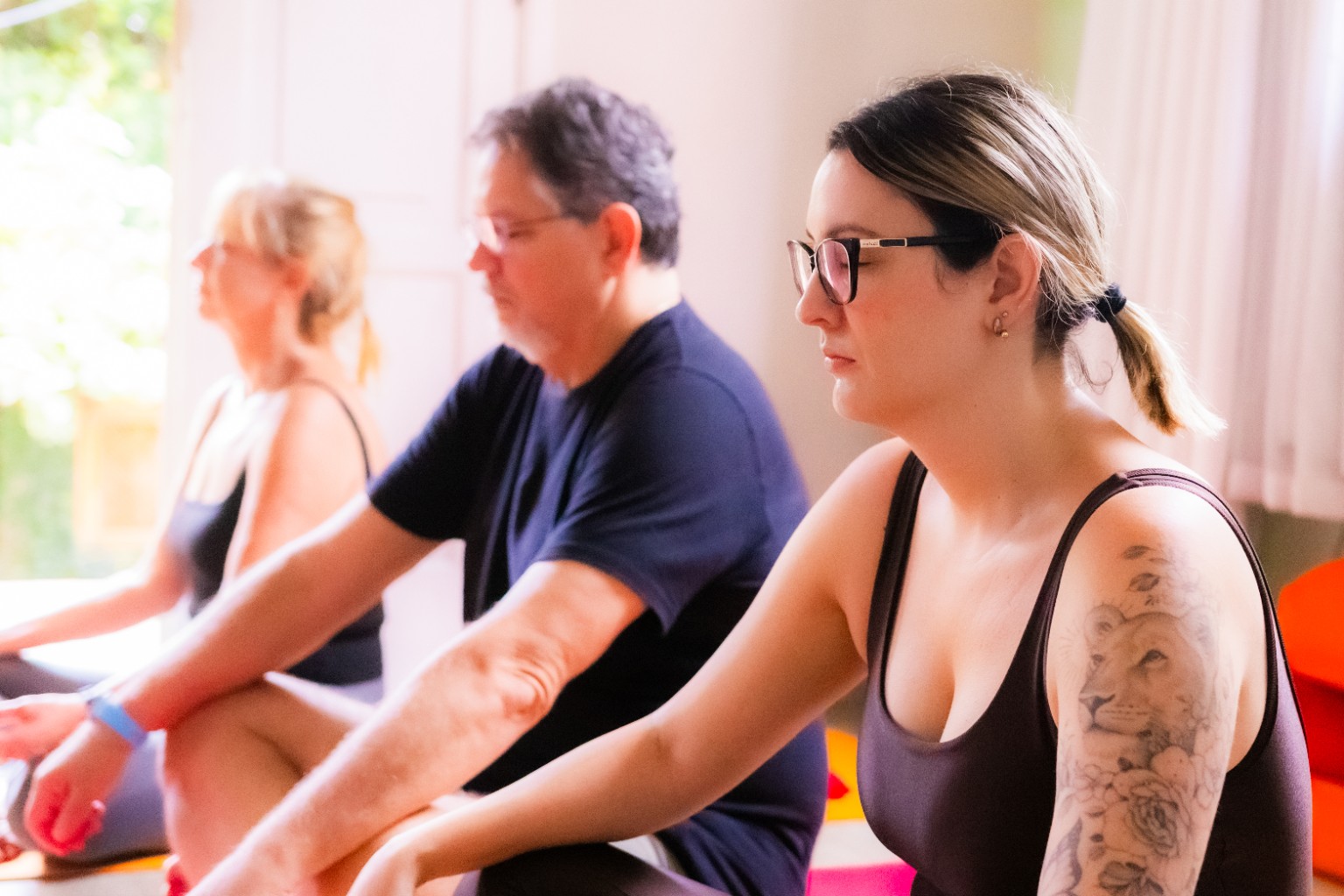 Participantes sentadas nos tapetes durante a aula de Yoga