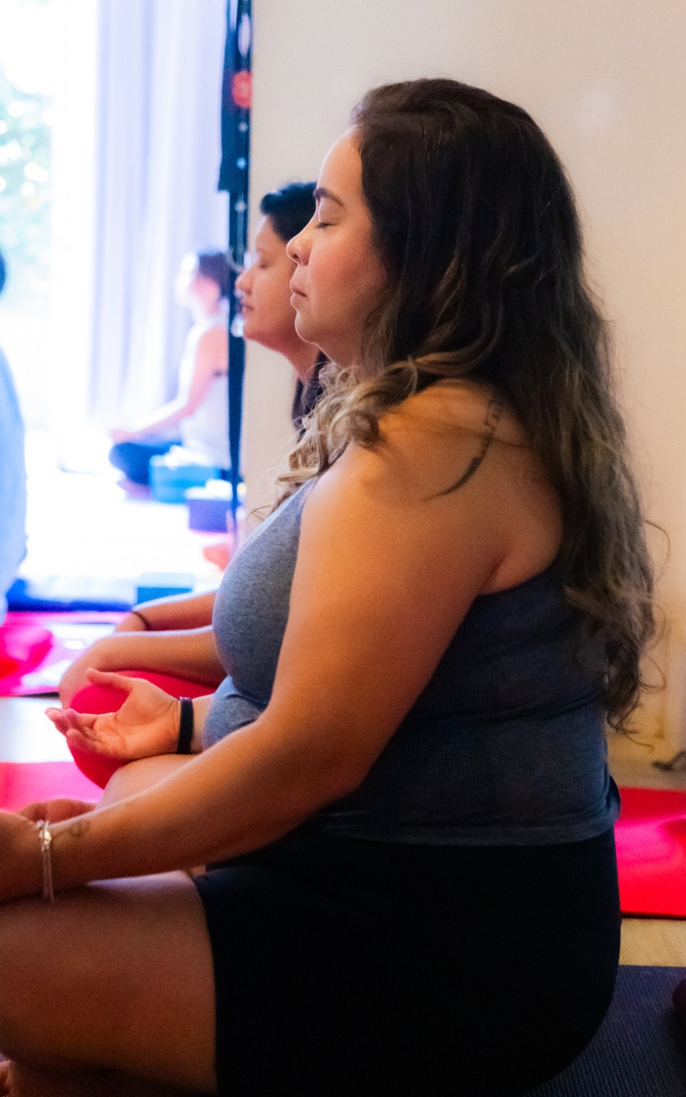 Participante sentada de perfil durante a aula de Yoga